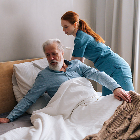 An assistant helping an elderly man stand up