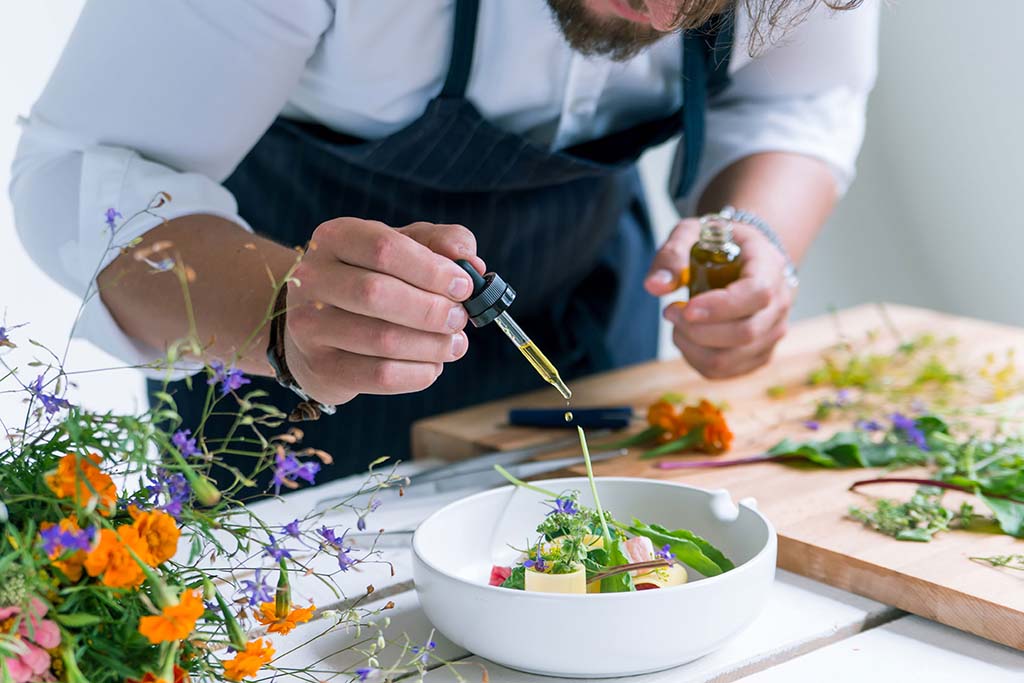 Chef using dropper to put olive oil on a salad